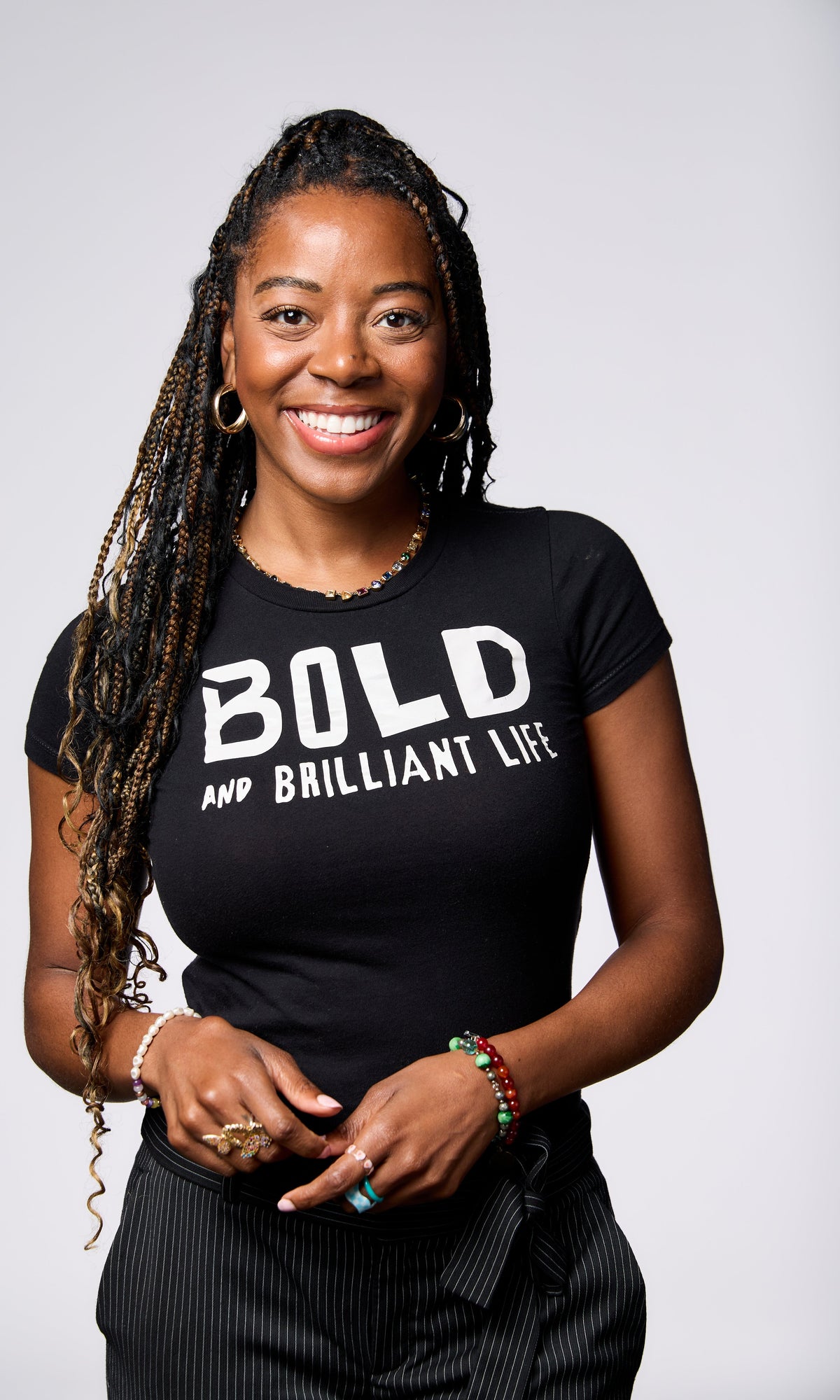 Woman (BIANCA PEART) wearing a black t-shirt with 'BOLD AND BRILLIANT LIFE' text on a white background